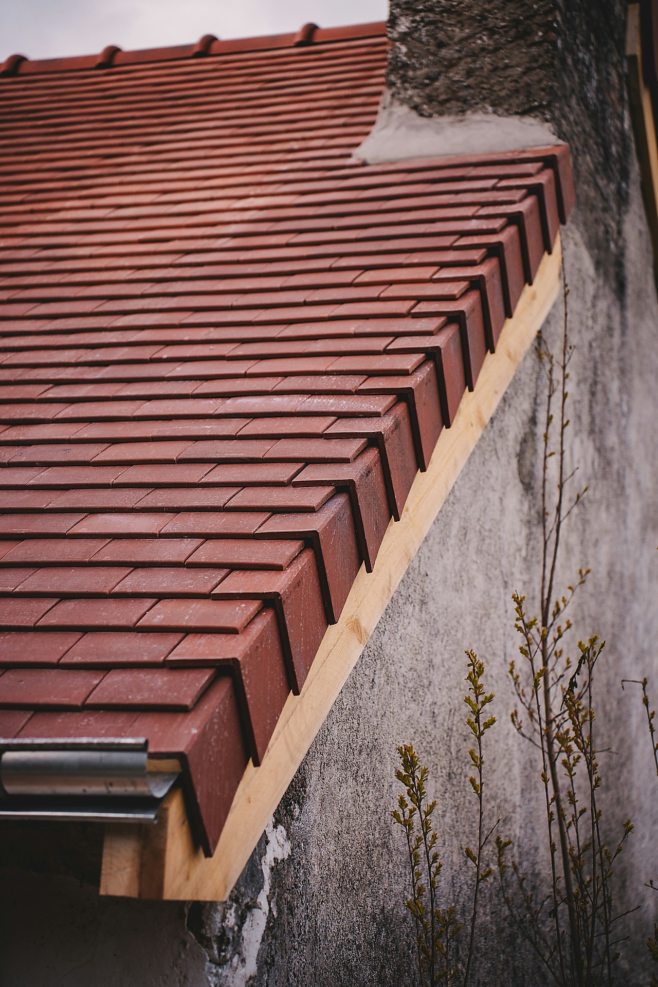 New white gutter installed along a tiled residential roof